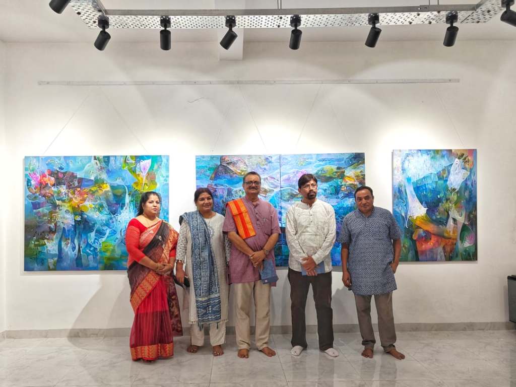 Group of five people standing in an art gallery, posing in front of colorful abstract paintings.