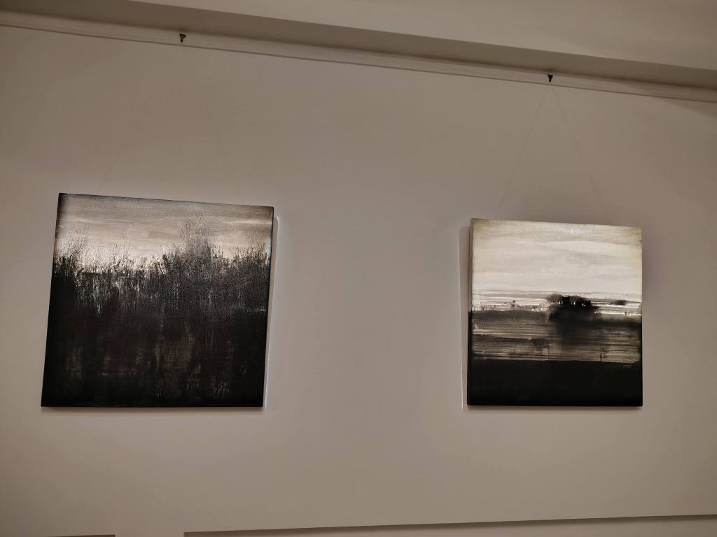 Two abstract black and white paintings displayed on a wall.