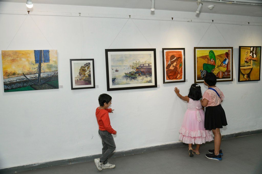 Children admiring artwork in a gallery, with several framed paintings displayed on the wall.