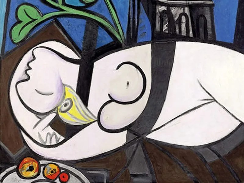 A colorful abstract painting featuring a reclining nude figure with prominent facial and body features, surrounded by geometric shapes and a small bowl of fruit.