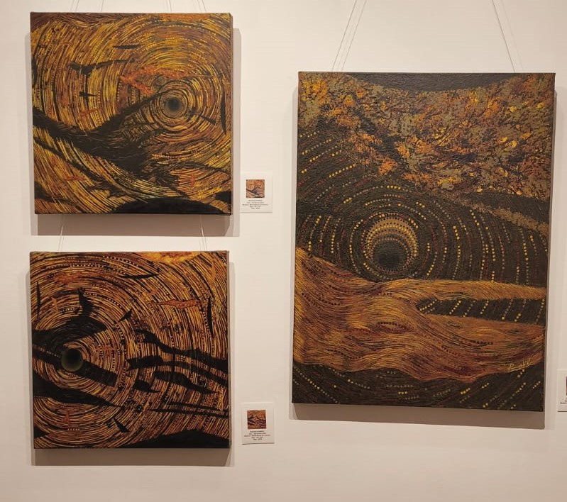 Three abstract paintings with swirling patterns in earthy tones of brown, black, and gold, displayed on a white wall.