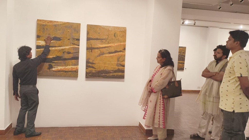 An artist discusses two abstract paintings on display in an art gallery, while four people listen attentively.