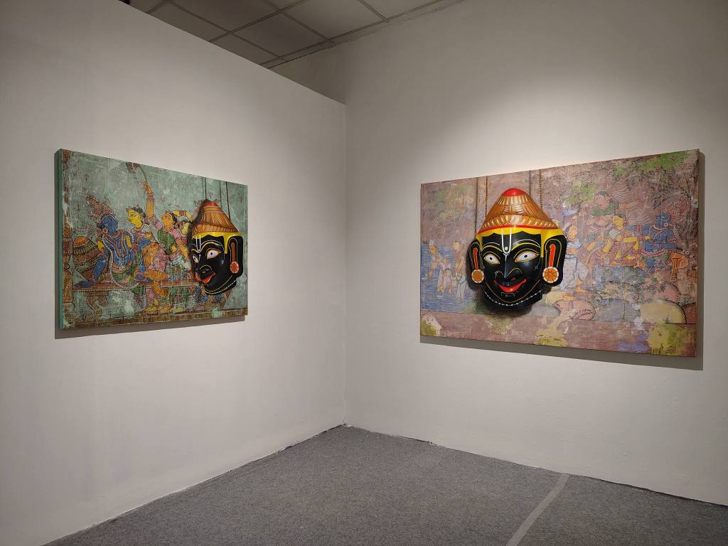 An art gallery with two paintings on white walls; the left features vibrant figures from a narrative scene, and the right showcases a traditional mask in front of a colorful background.